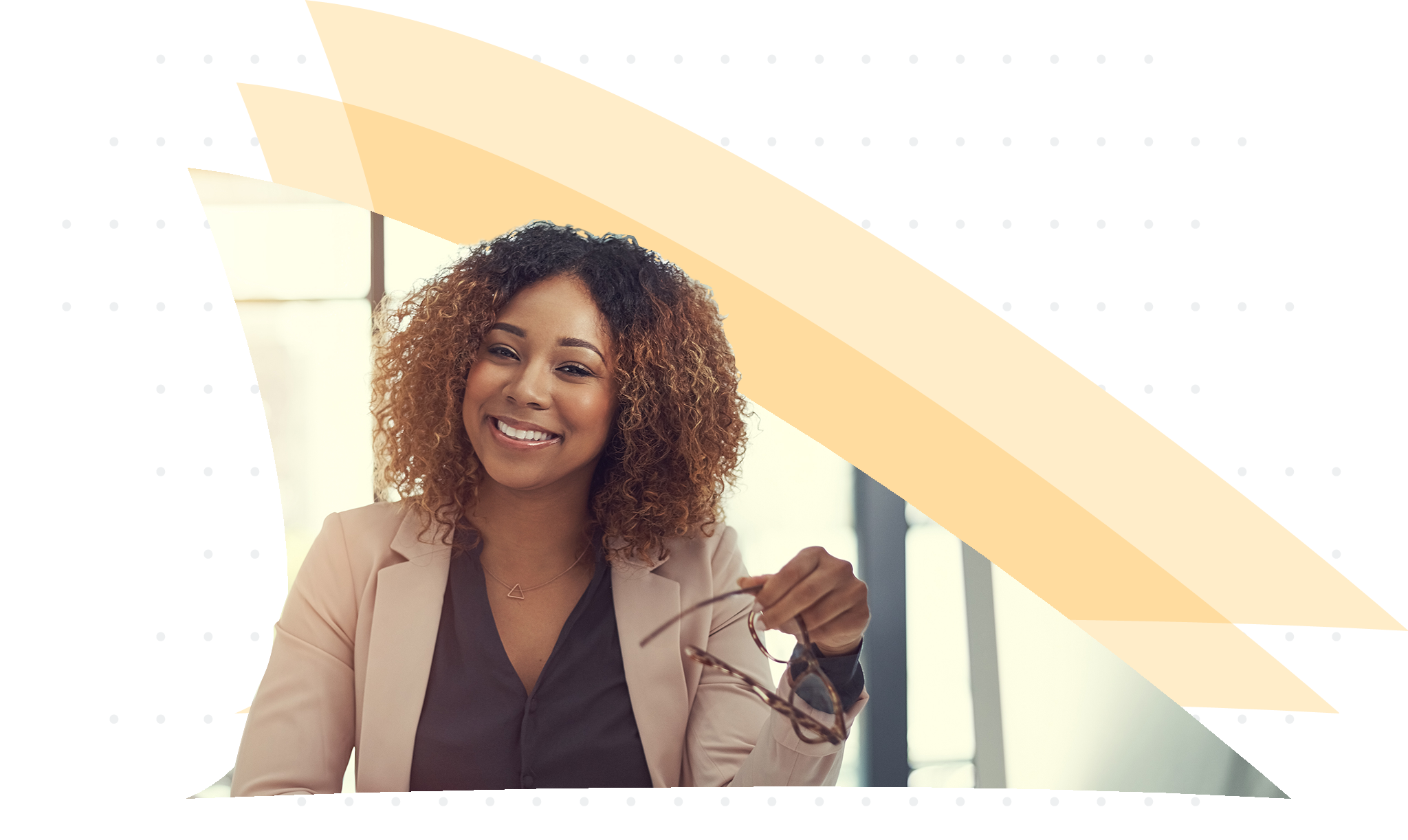 Professional woman holding glasses while sitting at a computer and smiling